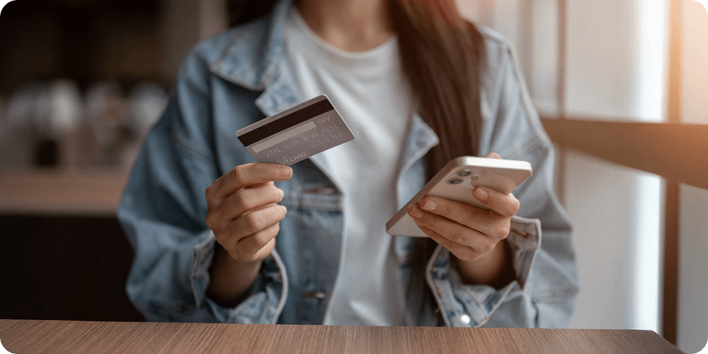 Step-by-step visual guide to redeem digital gift cards online using a smartphone. A person holding a credit card and smartphone to redeem digital gift cards online, showing the process of entering codes securely through mobile or app stores.